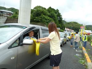 ドライバーに安全運転のチラシを手渡すショウさん