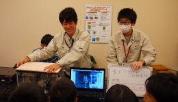 「スピーカーによるワイングラスの共鳴破壊実験」を説明する機械工学科の学生