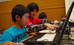 「ロボットで遊ぼう！」で真剣な表情でロボットを動かすためのプログラムを作成するこどもたち